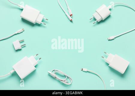 Frame made from modern power adapters, plug head and different USB cables on turquoise background Stock Photo