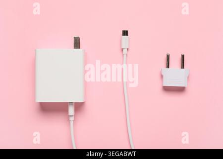 Modern power adapter, USB cable and plug head on pink background, top view Stock Photo