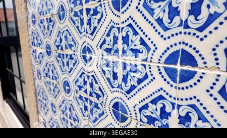 A sharp, side-angled perspective of classic blue and white Portuguese azulejo tiles, highlighting the repeating ornate floral motifs and dotted grid p Stock Photo