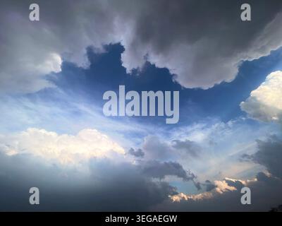 Dramatic Cloudscape with Blue Sky Opening and Sunlit Storm Clouds Background Stock Photo