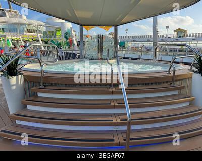 Large hot tub jacuzzi with stairs and stainless steel railings on an outdoor deck under a canopy. Stock Photo