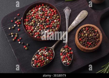 Food, Spice allspice of different colors pink, white, green not ground in a wooden saucer on a dark concrete background Stock Photo