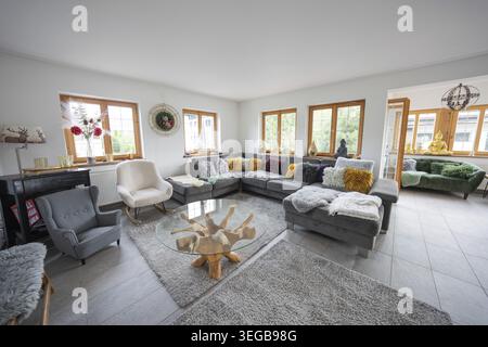 Cosy living room with large sofa, colorful pillows and a unique wooden table, flooded with light, holiday apartment, Gundhabing, Austria Stock Photo