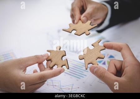 Concept of teamwork and partnership. Hands join puzzle pieces in the office. business people putting the jigsaws team together. Stock Photo