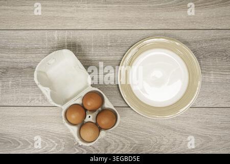 Four eggs in a carton box on the wooden table Stock Photo