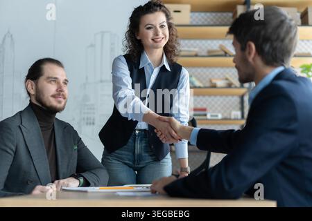Happy businessman and businesswoman shaking hands at group board meeting. Professional business executive leaders making handshake agreement successfu Stock Photo
