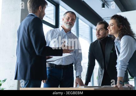 Executive business team people group working with paperwork standing at table, analyzing corporate strategy concept, reviewing plan, managing financia Stock Photo