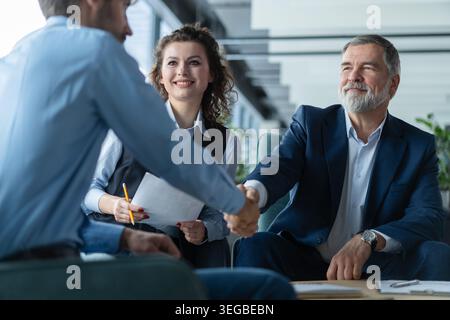 Happy businessmen shaking hands at group board meeting. Professional business executive leaders making handshake agreement successful company trade pa Stock Photo