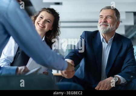Happy businessmen shaking hands at group board meeting. Professional business executive leaders making handshake agreement successful company trade pa Stock Photo