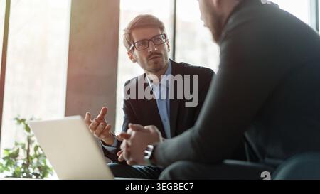 Businessmen discussing deal, sharing startup ideas, business partners negotiations or job interview in modern office, colleagues talking, working on p Stock Photo