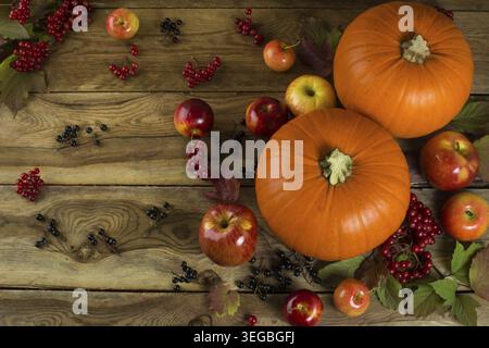Ripe pumpkins, apples, berries and leaves on wooden background. Selective focus. The toning Stock Photo