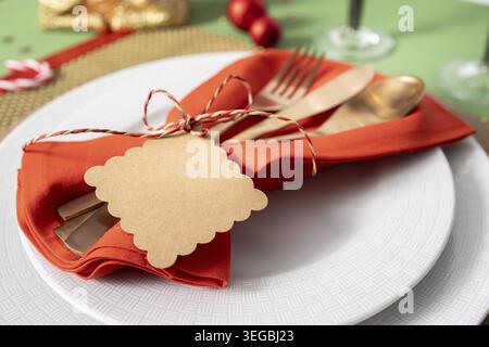 Close-up view of modern cutlery with a blank label on a red napkin, placed on top of prepared dishes on a Christmas dinner table. Template mockup Stock Photo