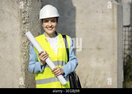 Portrait of a happy female architect holding blueprints on a construction site, on her first major project. Copy space Stock Photo