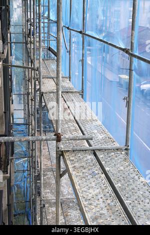 Scaffolding structure providing temporary access with platforms and protective netting for a building renovation project Stock Photo
