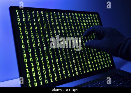 Hacked or hacking computer concept. Gloved Hand, Binary code and hacked word on laptop computer screen Stock Photo