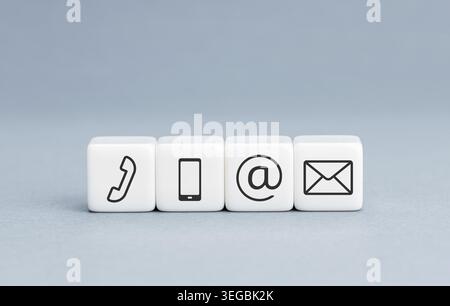 Contact us icons on white cube blocks on blue background. Copy space Stock Photo