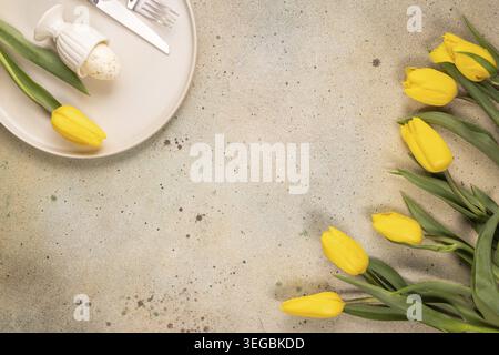 Easter egg on a plate with yellow tulips Stock Photo