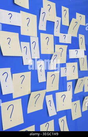 Memo sheets on the wall with many question marks Stock Photo