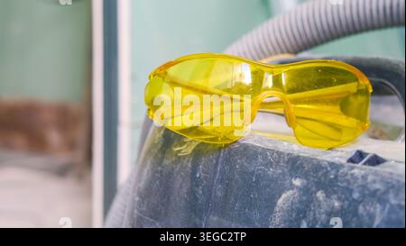 Pair of yellow plastic safety glasses for safe work during construction, renovation, repair and maintenance. PPE protective accessory. Industrial work Stock Photo
