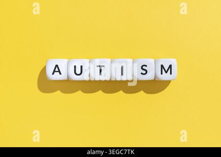 Autism word on white cube blocks isolated on yellow background Stock Photo