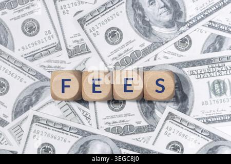 FEES word on wooden blocks and US dollar bills background Stock Photo