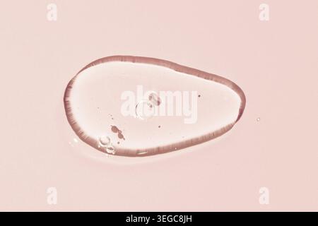 Transparent Liquid gel cosmetic smudge texture. Clear liquid gel with bubbles drop isolated on pink background Stock Photo