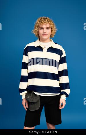 Blonde curly haired student showcases unique fashion in a vibrant studio setting Stock Photo