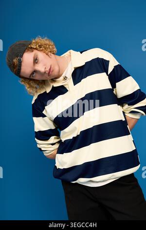 Blonde, curly haired guy showcases his unique fashion in a modern studio environment. Stock Photo