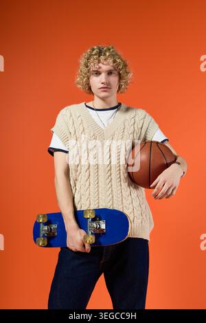 Blonde curly haired student showcases his trendy fashion with a skateboard and basketball. Stock Photo