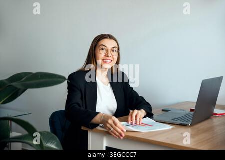 Woman working with documents and laptop at office desk. Business. Office work. Beautiful female professional analyzing data. Beauty portrait. Corporat Stock Photo