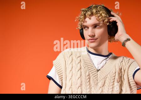 Blonde curly haired student showcases unique fashion while enjoying music in studio light. Stock Photo