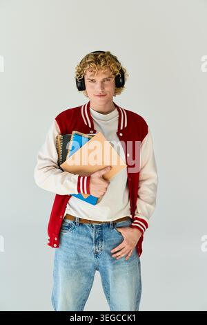 Blonde, curly haired student showcases his unique fashion while holding notebooks. Stock Photo