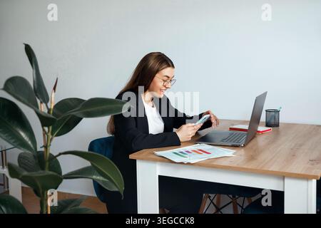 Woman working with laptop and financial documents at office desk. Business. Office work. Pretty female professional analyzing data. Beauty portrait. C Stock Photo