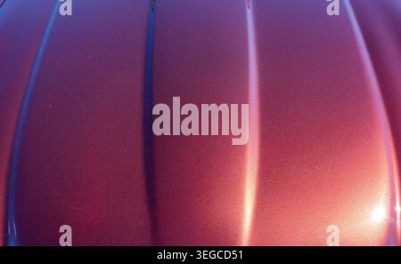 Metallic car bodywork with deep purple and red candy paint finish showing raised bonnet ridges and specular light reflections Stock Photo