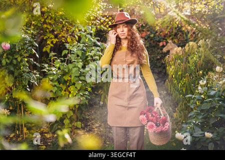 Red Haired Woman Holding Dahlia Bouquet In Nordic Garden Stock Photo