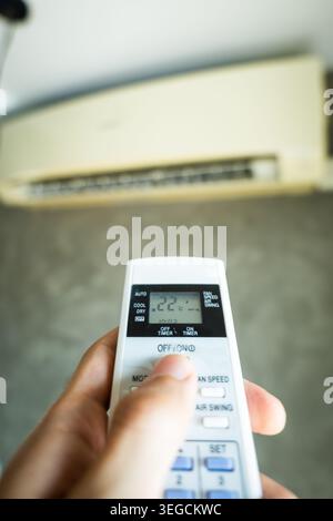 Air conditioner temperature adjustment with remote controller in room at home Stock Photo