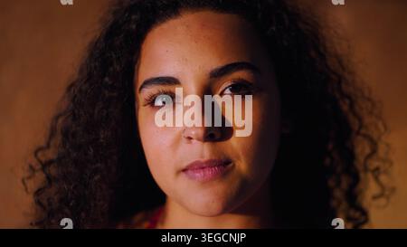 Young woman with natural curly hair and nose ring looking directly at viewer Stock Photo