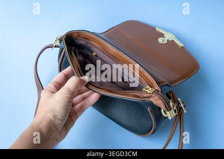 Showing inner part of a ladies handbag, empty inside, no money. Isolated on light blue background. Stock Photo