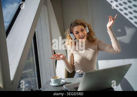 Happy young woman enjoying music and dancing at cafe Stock Photo