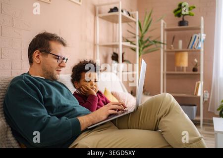 Father and son using laptop for remote work and learning Stock Photo