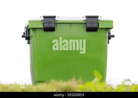 Large new green waste container in front of a blue sky and grass in front Stock Photo