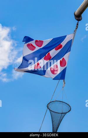 Dutch flag of the province Friesland hanging on a rope of a fishing ship Stock Photo