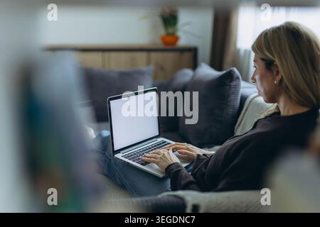 Woman working remotely from home on laptop in cozy living room home office environment. High quality photo Stock Photo