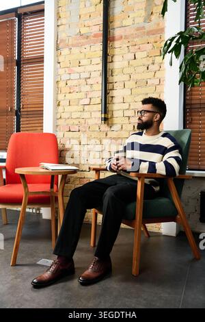 A young man sits comfortably in a trendy room, enjoying a moment of peace and style. Stock Photo