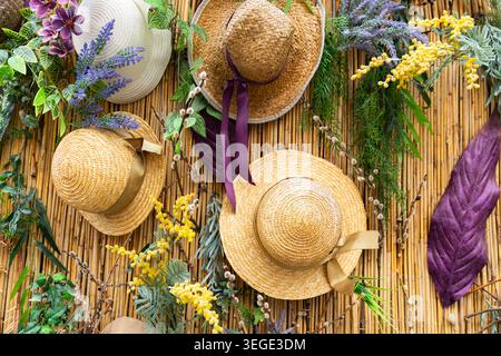 Decorative bamboo wall decorated with straw hats, mimosa, lavender and spring flowers Stock Photo