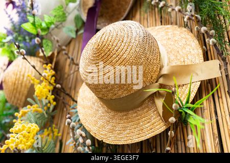 Decorative bamboo wall decorated with straw hats, mimosa, lavender and spring flowers Stock Photo