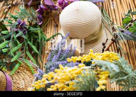 Decorative bamboo wall decorated with straw hats, mimosa, lavender and spring flowers Stock Photo