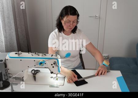 Close up of woman marking fabric with tailor tools during sewing and dressmaking process. Detailed textile preparation with measuring accessories and Stock Photo