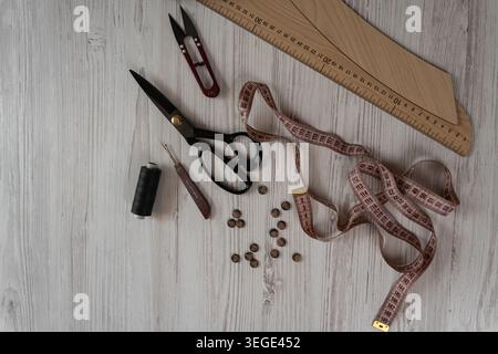 Collection of sewing tools and tailoring accessories including scissors, measuring tape, ruler, threads and buttons arranged on table. Concept of hand Stock Photo