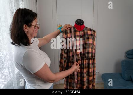 Woman taking body measurements on professional tailor mannequin during dressmaking and sewing process in atelier. Fashion designer working with measur Stock Photo